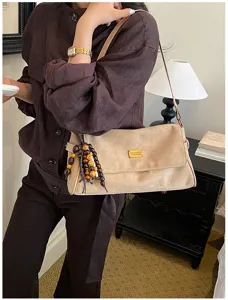Vue détaillée d'un sac à bandoulière rétro en suédine avec perles en bois et plaque.