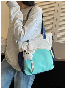 Vue de détail rapprochée du sac cabas color-block élégant avec un porte-clés en peluche.