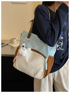 Gros plan détaillé du cabas élégant à blocs de couleurs avec pendentif en peluche et bandoulière.