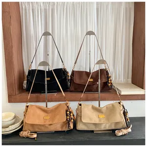 Vue détaillée du sac bandoulière rétro en suédine avec plaque en métal et breloques en perles