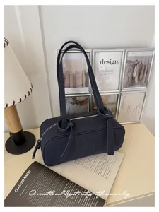 Close-up of a minimalist dark navy cylinder shoulder bag showcasing elegant knot strap details.