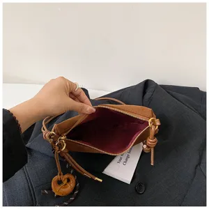 Vintage brown suede crossbody dumpling bag with zipper and cute charm, casual daily handbag.