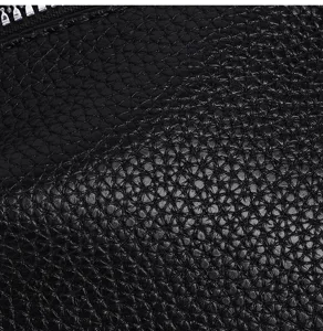Black textured leather wallet detail close-up showing premium material and metal zipper.