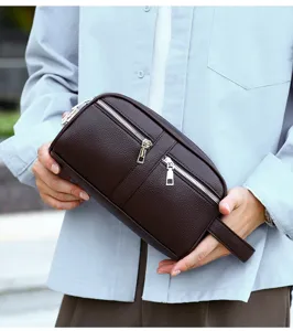 Dark brown leather mens clutch bag detail view with zipper pockets and wrist strap