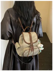 Achterkant detail van casual minimalistische rugzak met leeraccenten en schattige hanger.