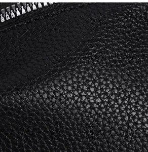 Close-up detail view of the black leather texture and metal zipper on the stylish men's clutch bag.