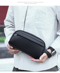 Detail shot of black leather men's clutch bag with wrist strap, showing texture and design.