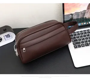 Detailed view of dark brown leather travel toiletry bag, commuter clutch with handle and zipper.