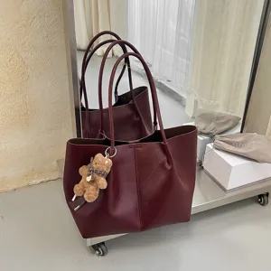 Clásico bolso tote de piel sintética burdeos con correas largas y colgante de osito tierno.