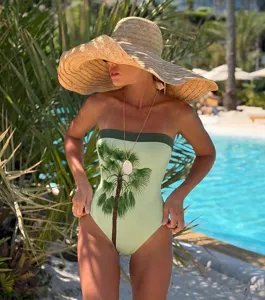 Detail shot of trendy strapless one-piece swimsuit with tropical palm tree print for beach vacation.