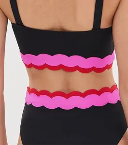 Black two-piece swimsuit with pink and red scalloped trims for stylish beach wear.