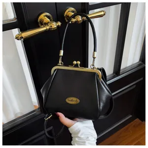 Detailed close-up of a vintage black kiss-lock shoulder bag with elegant gold hardware.