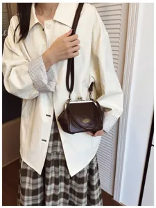 Close-up detail of the retro dark brown kiss-lock crossbody bag worn by model, stylish aesthetic.