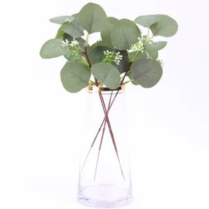 Artificial eucalyptus leaves in clear glass vase, fake green plants for home decoration.