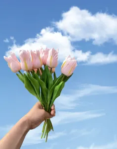 Detail shot of artificial PU tulip flowers showing realistic pink petals and green leaves closeup.