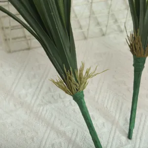 Artificial flower stem closeup showing realistic green leaves and root details for floral decor.