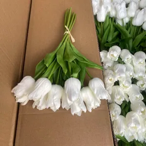 Close-up detail of white artificial PU tulip bouquet with realistic petals and green leaves.