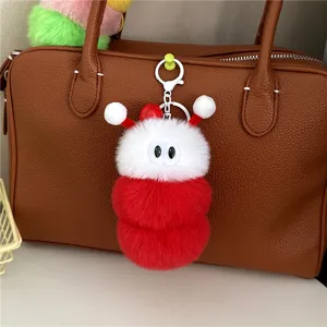 Nahaufnahme eines niedlichen Plüsch-Raupen-Schlüsselanhängers an einer braunen Tasche.