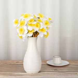 Artificial white and yellow daffodil flower bouquet in a modern white ceramic vase for home decor detail.