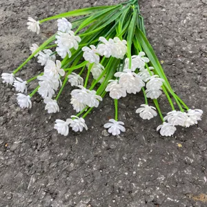 Gedetailleerde close-up van een wit kunststof bloemenboeket met groene stelen voor decor.