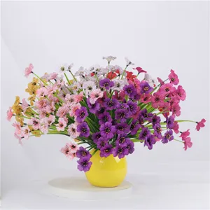 Closeup detail of vibrant artificial violet silk flowers in a yellow vase for home decor.