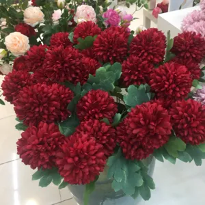 Detail van een kunstmatig rood chrysantenboeket, ideaal voor huisdecoratie en tafelweergave.