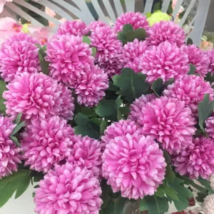 Close-up detail van een weelderig roze kunstbloemboeket met groene bladeren voor thuis.