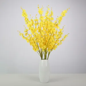 Close-up of vibrant yellow artificial dancing orchid stems in a sleek white ceramic vase.