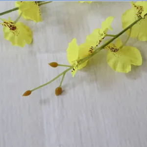 Detailed close-up shot of artificial yellow dancing orchid flower branch with spots.