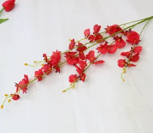 Close-up detail shot of red artificial dancing orchid silk flower branch, home decor display.