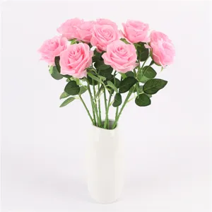 Detailed shot of pink artificial silk rose bouquet in white vase for home wedding decor.