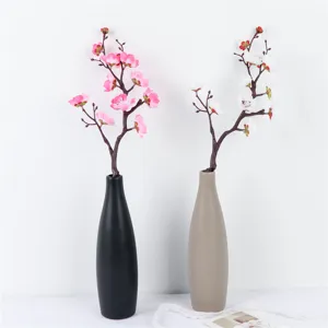 Artificial plum blossom branches with ceramic vase for home decoration and room interior setup.