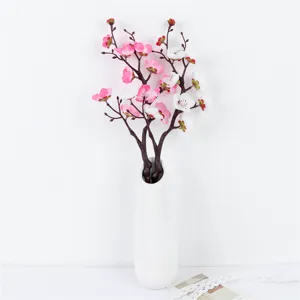 Artificial plum blossom branch detail shot featuring pink and white flowers in a white vase.