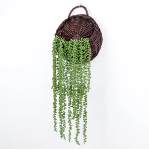 Detailed view of artificial string of pearls hanging in brown wicker basket for wall decor.
