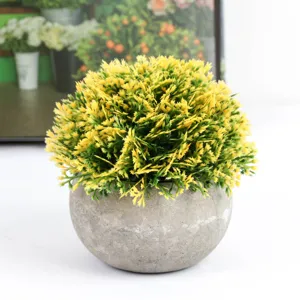 Close-up detail of artificial yellow green potted plant in grey round pot for home decor.