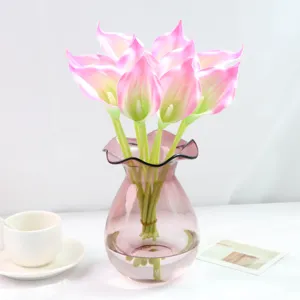 Détail en gros plan d'un bouquet de lys calla artificiels roses dans un vase en verre.