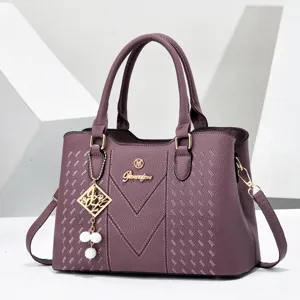 Purple leather shoulder bag detail, elegant metal logo accent, textured finish pendant.