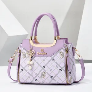 Purple quilted handbag detail featuring cute bear print, gold hardware, and pearl heart charm.