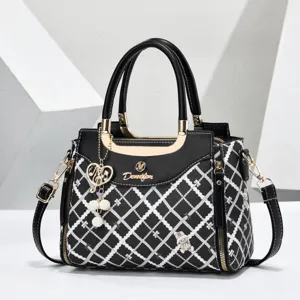 Detailed view of fashionable black diamond lattice shoulder bag with top handle and gold hardware.