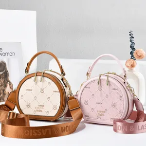 Stylish PU leather round crossbody bag with cute cartoon prints and wide strap for women.