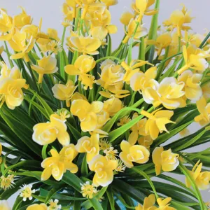 Close-up detail of artificial yellow orchid flowers and green leaves, perfect for decor.