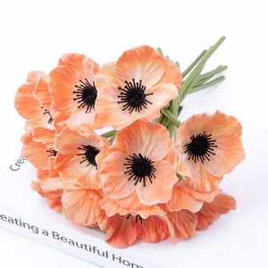 Primo piano dettagliato di vivaci fiori di papavero artificiali arancioni con centri neri.