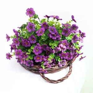 Primo piano dettagliato di fiori viola artificiali e foglie verdi nel cesto rustico.