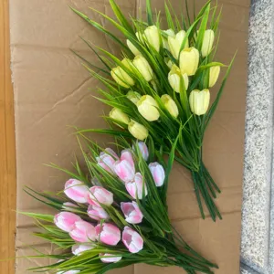 Artificial tulip bouquet detail shot, vibrant yellow and pink flower bunch with green leaves.