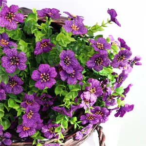 Fiori di seta viola artificiali con foglie di eucalipto in un cesto intrecciato.