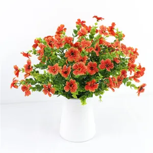 Bouquet di fiori artificiali con fiori arancioni e foglie di eucalipto in un vaso bianco.