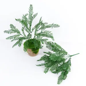 Vue de détail de fougère Boston artificielle avec pot de mousse et branche, décor plastique.