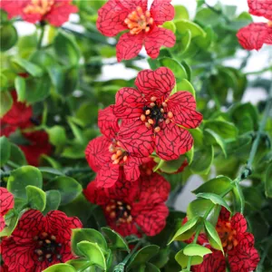 Primo piano dettagliato di fiori rossi artificiali con foglie verdi per la decorazione.