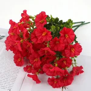 Close-up detail of artificial red morning glory flower bouquet with green leaves for home decor.
