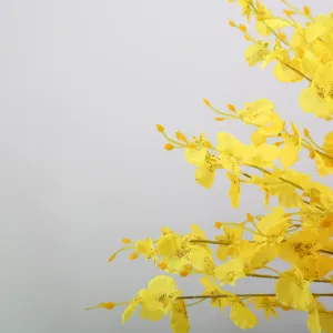 Close-up view of yellow artificial dancing orchid branches, detailed fabric silk flower decor.